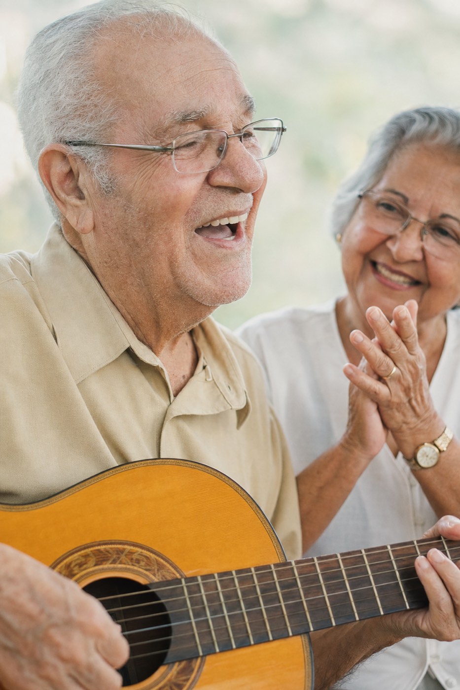 Idoso tocando violão ao lado de uma amiga